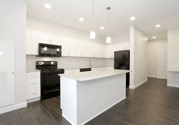 Large island kitchen with pendant lighting, designer plank flooring, and granite counterops.